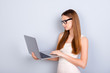 © deagreez - Success and work, study concept. Young serious lady journalist is working on her laptop, wearing casual clothes and glasses, on pure light background