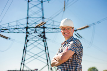 Experienced engineer with white hard hat under the power lines. Engineer work at an electrical substation.