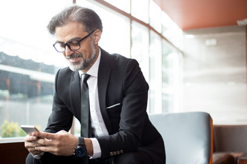 Smiling senior man checking message on phone