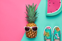 Fashion Hipster Pineapple Fruit. Bright Summer Color, Accessories. Tropical Pineapple With Sunglasses, Stylish Handbag Creative Art Concept. Minimal Style. Pink Blue Summer Party Background
