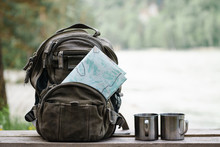 Backpack With Maps And Two Mugs.