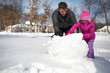 © Sarah Rypma - Father and daughter, outdoors in snow, building snowman