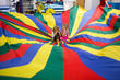 © Sarah Rypma - Children playing with colourful parachute, two girls sitting in middle of parachute