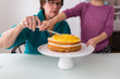 © Sarah Rypma - Grandmother and granddaughter assembling layer cake, mid section