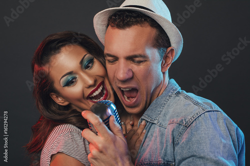 Plakat Szczęśliwa przystojna para w rocznika ubraniowym śpiewie w retro mikrofon