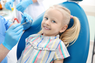 Wall Mural - Dentist examining little girl's teeth in clinic