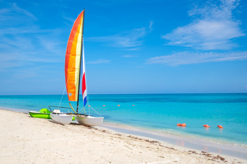 The tropical beach of Varadero in Cuba with a colorful sailboat