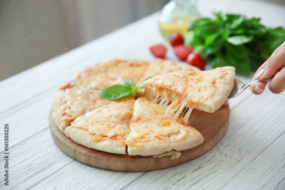 Tasty sliced pizza with basil leaves on wooden table