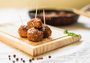 Wall Mural - Meatballs in tomato sauce on a wooden board with toothpicks against white background