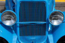Two Headlights And Grille Of  A Blue Classic Car