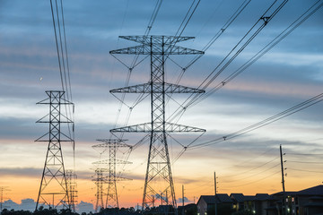 Wall Mural - Group silhouette of transmission towers (power tower, electricity pylon, steel lattice tower) at twilight in Humble, Texas, US. Texture high voltage pillar, overhead power line, industrial background.