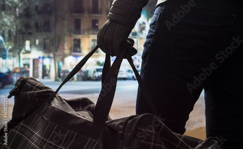 Fotomural Terrorist standing and holding black bomb bag in hand with leather gloves