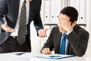 Young businessman getting stressed by his boss at the meeting