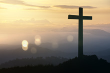 Concept Conceptual Black Cross Religion Symbol Silhouette In Grass Over Sunset Or Sunrise Sky