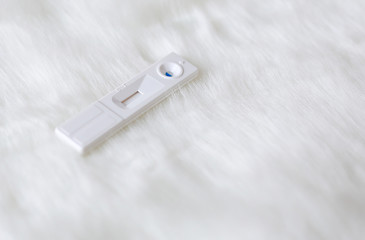 Pregnancy test on artificial white fur background..