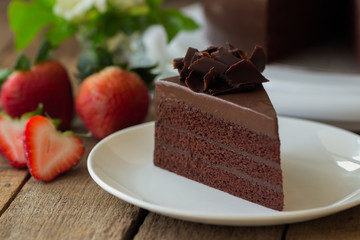 Homemade bakery: chocolate fudge cake decorated with chocolate curl. Triangle slice piece of chocolate cake on rustic wood table for cafe,meeting, coffee break or tea time and birthday party.