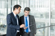 © Atstock Productions - Businessmen discussing work at office building corridor