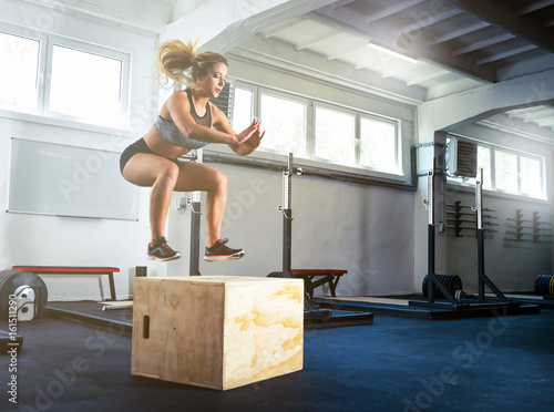 Fotografia Fitness woman jumping on box training at the gym, crossfit exercise