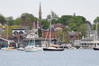 Newport Harbor in Newport, Rhode Island. The brown steeple is the historic St. Mary's Church where John F. Kennedy was married. Sailboats and moorings are in the foreground. Seaside, coastal town