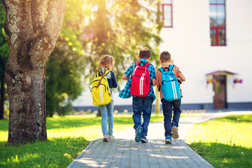 children with rucksacks standing in the park near school. pupils with books and backpacks outdoors