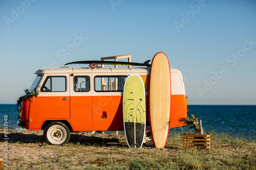 Fotomural bus with a surfboard on the roof is a parked near the beach