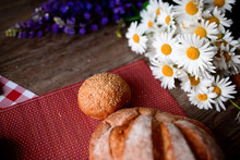 Close Up On Traditional Bread On The Table, Next To Flowers Daisies And Lupins