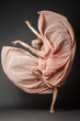 © julenochek - Woman in light chiffon dress dancing sensually on black plain background.