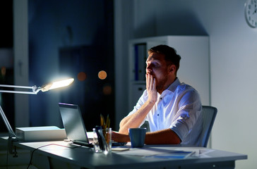 man with laptop and coffee working at night office