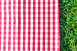 Red gingham tablecloth on green grass with copyspace