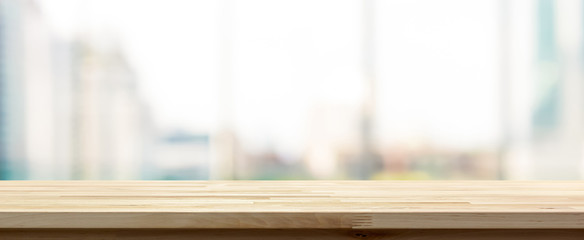 Wood table top on blur  city building view background looking through glass window, panoramic banner