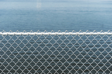 Wall Mural - chainlink fence against blue sea