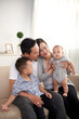 © DragonImages - Portrait of young Asian family playing with adorable little kids at home, sitting on sofa