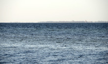 Mirage Over The Sea, The Land In The Background With No Less That 3 Lighthouses Seems To Hover On The Water Surface.