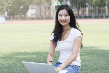 Wall Mural - Female college student in playground use laptop