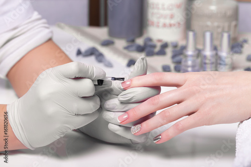 Photographie Closeup finger nail care by manicure specialist in beauty salon