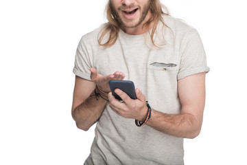 Wall Mural - excited young blond man using smartphone, isolated on white