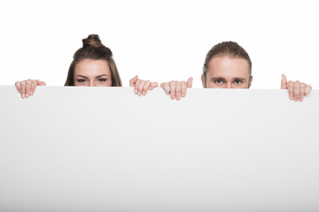 Wall Mural - Young couple holding blank white card and looking at camera