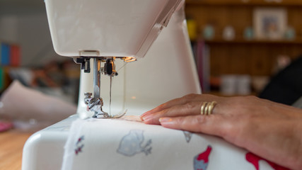 female hand using sewing machine stitching fabic