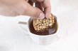 Hand dipping homemade cookies with cereals and sunflower seeds in a cup of tea on a white background