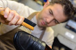worker polishing using a horsehair brush for leather shoe