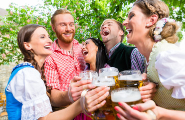 Wall Mural - Fünf Freunde, Männer und Frauen, haben Spass in Biergarten beim Anstoßen mit Maßkrügen