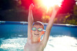© sakkmesterke - Happy kid enjoying summer sunset in swimming pool in sunset, hands up in the air