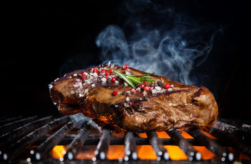 Wall Mural - Beef steak on the grill grate, flames on background