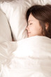 © fizkes - Young attractive woman sleeping in soft bed under warm blanket. Teenage girl falling asleep in bedroom after night party, seeing pleasant dreams in soft bed with fresh white sheets. View from above