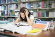 © Prasit Rodphan - Young Asian student under mental pressure while reading book preparing examination in library at university. Asian student looking stressed..