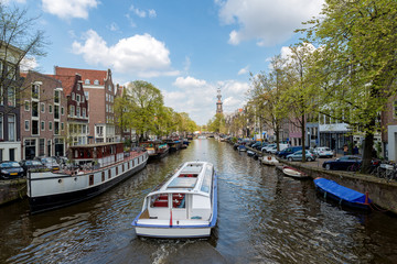 Amsterdam canal cruise ship with Netherlands traditional house in Amsterdam, Netherlands.