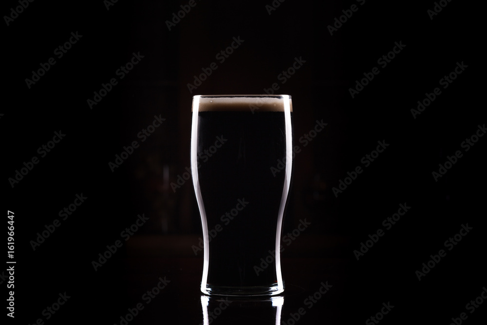 Stout (Guinness like) Beer in pint glass, silhouette with perfect head and dark background - obrazy, fototapety, plakaty 