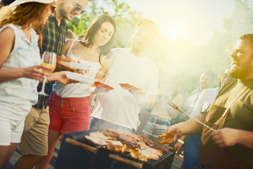 Group of friends eating, drinking, dancing and having a good time at outdoor party