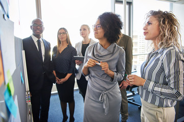 Colleagues strategizing together on a whiteboard in an office