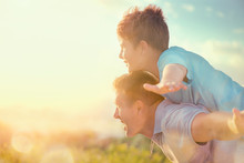 Happy Father And Son Having Fun Over Beautiful Sky Outdoors. Summer Holidays, Vacation